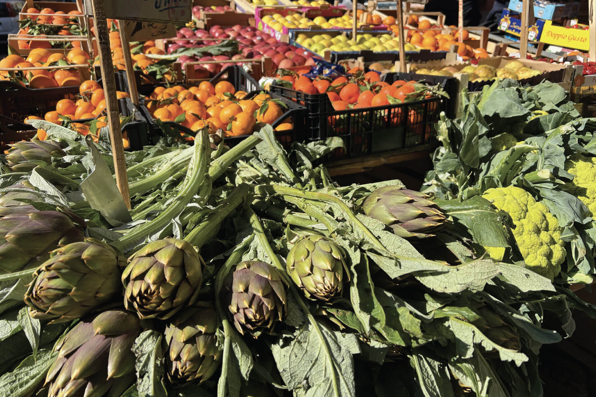 Fresh vegetables at Ballarò Market in Palermo, showcasing colorful artichokes, cauliflowers, and seasonal produce